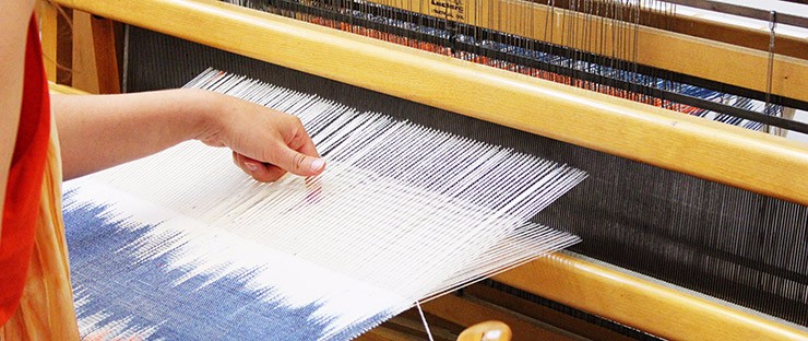 A student weaving on a four-harness floor loom