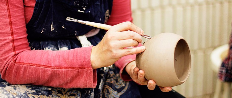A student carving a design into a vessel